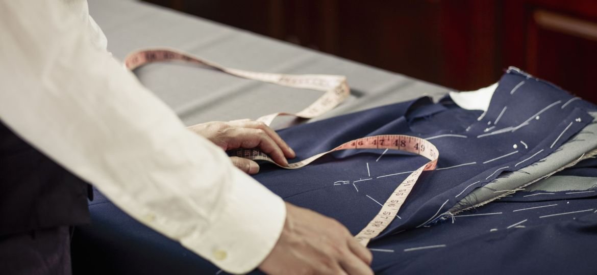 Tailor measuring garment on table in traditional tailors shop