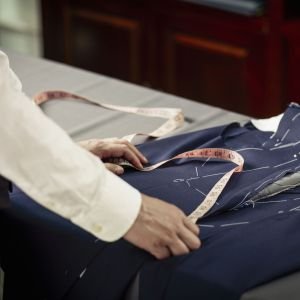 Tailor measuring garment on table in traditional tailors shop